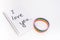 A notebook with I Love You inscription and lgbtq rainbow bracelet on white background