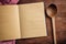 Notebook, kitchen ladle and red tablecloth on wooden table, top view, copy space