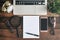 Notebook, laptop, magnifying glass, camera, phone and clock on a wooden table