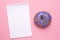 Notebook and lilac sweet donut on a pink background flat lay