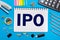 A Notebook with notes IPO, Initial Public Offering with office tools on yellow blue background. Concept of the choice of IPO.