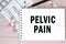 Notebook page with words - Pelvic Pain nearby with a pills and pencil, medical concept