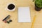 Notebook paper with pencils, coffee, thyme on flowerpot, stapler and paperclip on brown wood table background