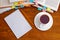 Notebook and pencil with a cup of tea in front of pile of books with bookmarks