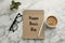 Notebook with phrase Happy Boss`s Day, coffee, glasses and plant on marble table, flat lay