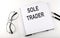 Notebook with text SOLE TRADER on the white background