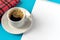 Notebook with white workspace for inscriptions next to a cup of coffee and a red napkin on a blue background