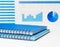 Notebooks in blue and blue with a spring on the table against the background of financial charts. Investment concept or business