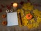 Notepad, decorative handmade textile pumpkins, candle, large pencil, autumn leaves on a textile background.