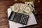 Notepad with dollars, pencil and calculator on wooden desk. Financial planning concept