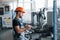 With notepad in hands. Industrial worker indoors in factory. Young technician with orange hard hat