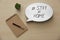 Notepad, houseplant and speech bubble with hashtag STAY AT HOME on wooden background, flat lay. Message to promote self-isolation