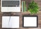 Notepad, laptop, green plant and tablet computer on wooden desk
