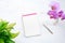 Notepad mockup with green plant and pink orchid