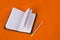 Notepad on an orange background. Notebook and pencil. school and education. Stationery