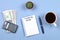 Notepad with pen, coffee, dollars, calculator and cactus on a blue background. Copy the space. Top view. Financial, marketing, bus