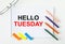 Notepad with text Hello Tuesday glasses colored pencils and colored stickers