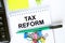 Notepad with text Tax Reform. Calculator, green pen stickers and stationary clips