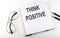 Notepad with text THINK POSITIVE . White background. Business concept