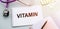 Notepad with text VITAMIN on desk, medical concept