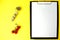 Notepad with a white sheet of paper for notes, next to it twisted centimeter and branch with red cherry tomatoes on a yellow