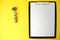 Notepad with a white sheet of paper for notes, next to it twisted centimeter on a yellow background. To-do list. Copy space.