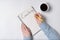 Notepad with word COACHING. Female hands and cup of coffee on white background. Top view