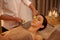 Nothing better than a facial to unwind. A beautiful young woman lying on a massage table at the spa with cucumer over