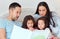 Nothing brings the family together like a good story. a man holding a storybook while sitting with his wife and two