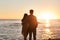 Nothing inspire romance like a sunset. Rearview shot of a happy young couple watching the sun go down at the beach.