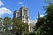 Notre Dame Cathedral from Seine river walk. Paris, France. Towers and spire. Sunny day with cluds.