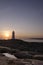 Nova Scotia lighthouse with sun setting over ocean.