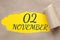 november 02. 02th day of the month, calendar date.Hole in paper with edges torn off. Yellow background is visible
