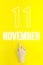 November 11st . Day 11 of month, Calendar date.Hand finger pointing at a calendar date on yellow background.Autumn month, day of