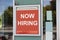 Now hiring sign outside modern office building