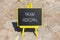 Now hiring symbol. Concept words Now hiring on beautiful black chalk blackboard. Beautiful sea stone beach background. Business