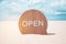 Now open sign board stand on sand summer beach background metaphor to time to travel relax tourism season with copyspace