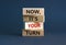 Now, it`s your turn symbol. Wooden blocks form the words `now, it`s your turn` on beautiful grey background. Businessman hand.