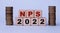 NPS 2022 - acronym on wooden cubes on a light background with coins