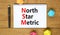 NSM north star metric symbol. Concept words NSM north star metric on white note on a beautiful wooden background. Metallic pen.