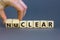 Nuclear or clear symbol. Businessman turns a cube and changes the word `nuclear` to `clear`. Beautiful grey background. Nuclea