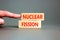 Nuclear fission symbol. Concept words Nuclear fission on beautiful wooden blocks. Beautiful grey table grey background.