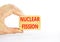 Nuclear fission symbol. Concept words Nuclear fission on beautiful wooden blocks. Beautiful white table white background.
