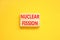 Nuclear fission symbol. Concept words Nuclear fission on beautiful wooden blocks. Beautiful yellow table yellow background.