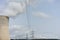 Nuclear power plant chimney with condensation smoke on a cloudy day with power pole electricity tower in the back