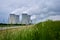 Nuclear power plant with four smoking chimneys in green nature meadows.