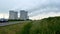 Nuclear power plant with four smoking chimneys in green nature meadows. Timelapse video.