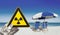 a nuclear radiation warning sign in front of blurred sun loungers and ocean