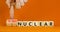 Nuclear or thermonuclear energy symbol. Concept words Nuclear or Thermonuclear on wooden cubes. Beautiful orange background.