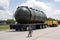 nuclear waste containment vessel being transported by truck, surrounded by armed security